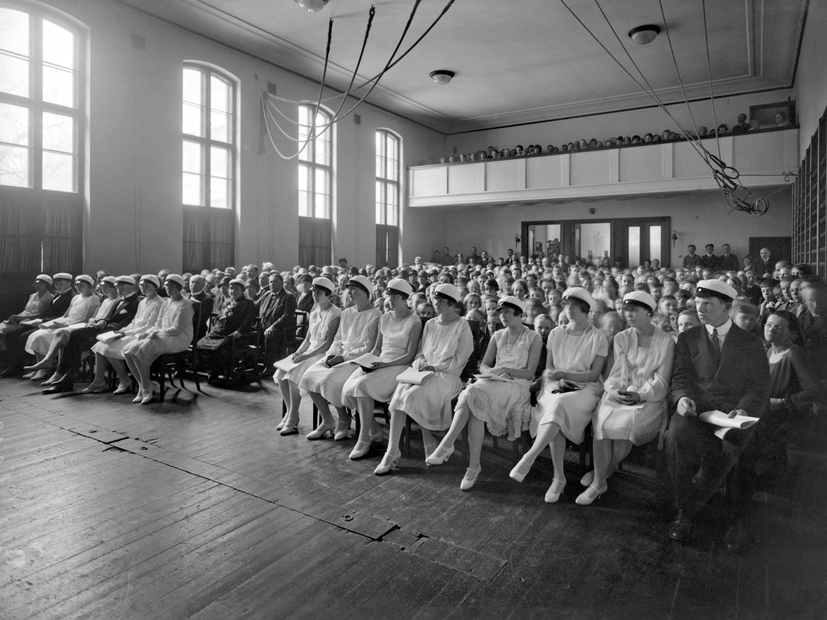 Vanhan ajan ylioppilaita suuressa salissa.