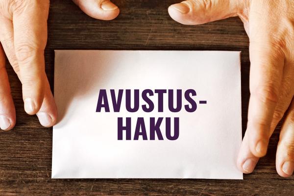 Ett kuvert med texten avustushaku mellan två händer.
