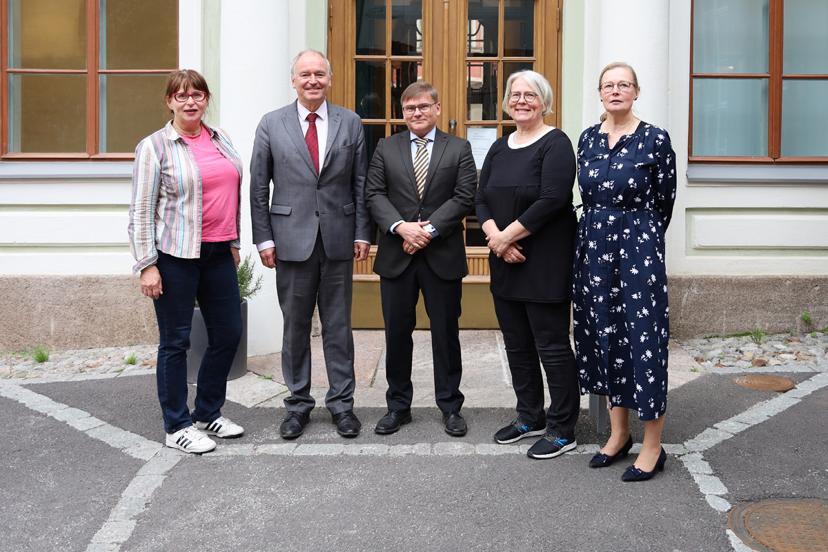 Viisi henkilöä seisoo vanhan rakennuksen edustalla.