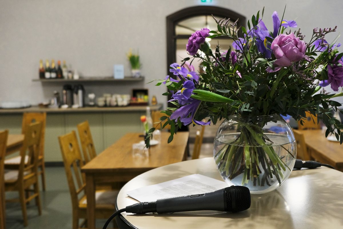 Kukkia lasisessa maljakossa ja mikrofoni pöydällä.