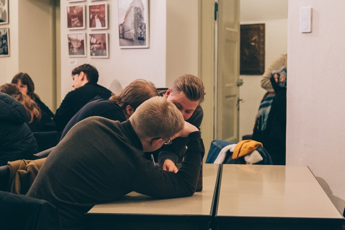 Ihmisiä kumartuneena keskustelemaan toistensa kanssa pöydän ympärillä.