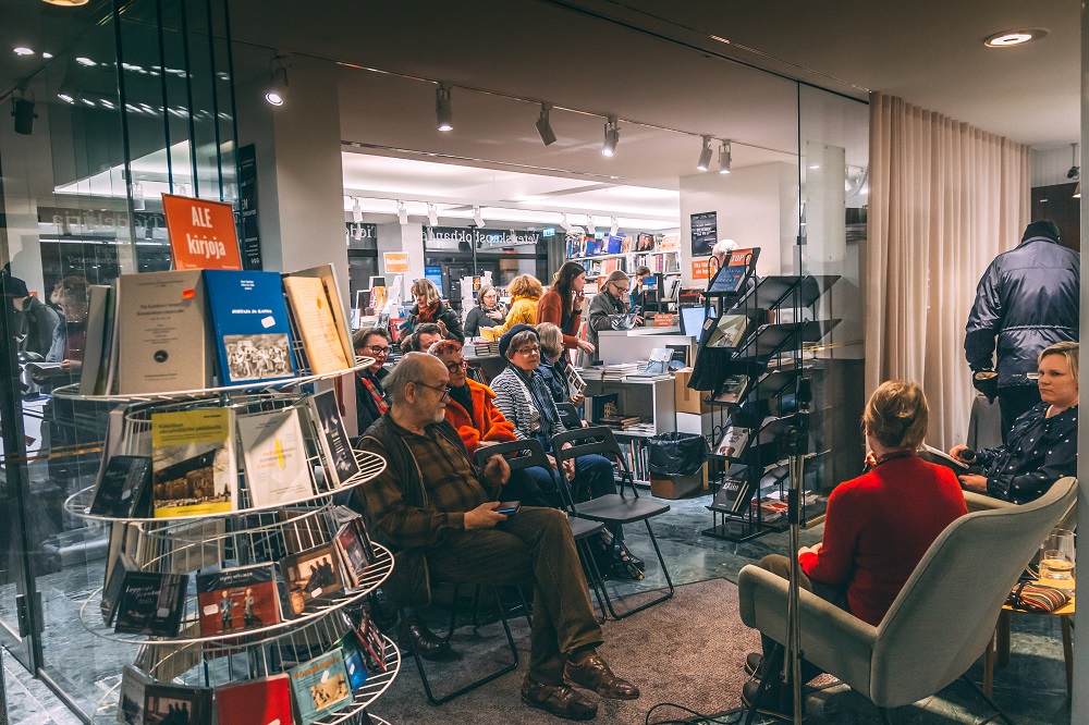 Kirjamyymälä, jossa paljon ihmisiä kuuntelemassa kahden ihmisen keskustelua.
